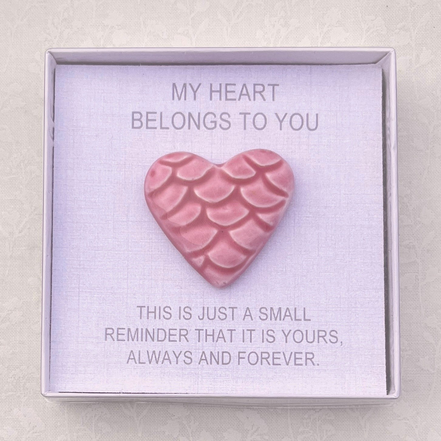 Pink heart-shaped ceramic in a box with sentimental text on a light gray background