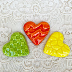 Three colored heart-shaped ceramics on a lace background.