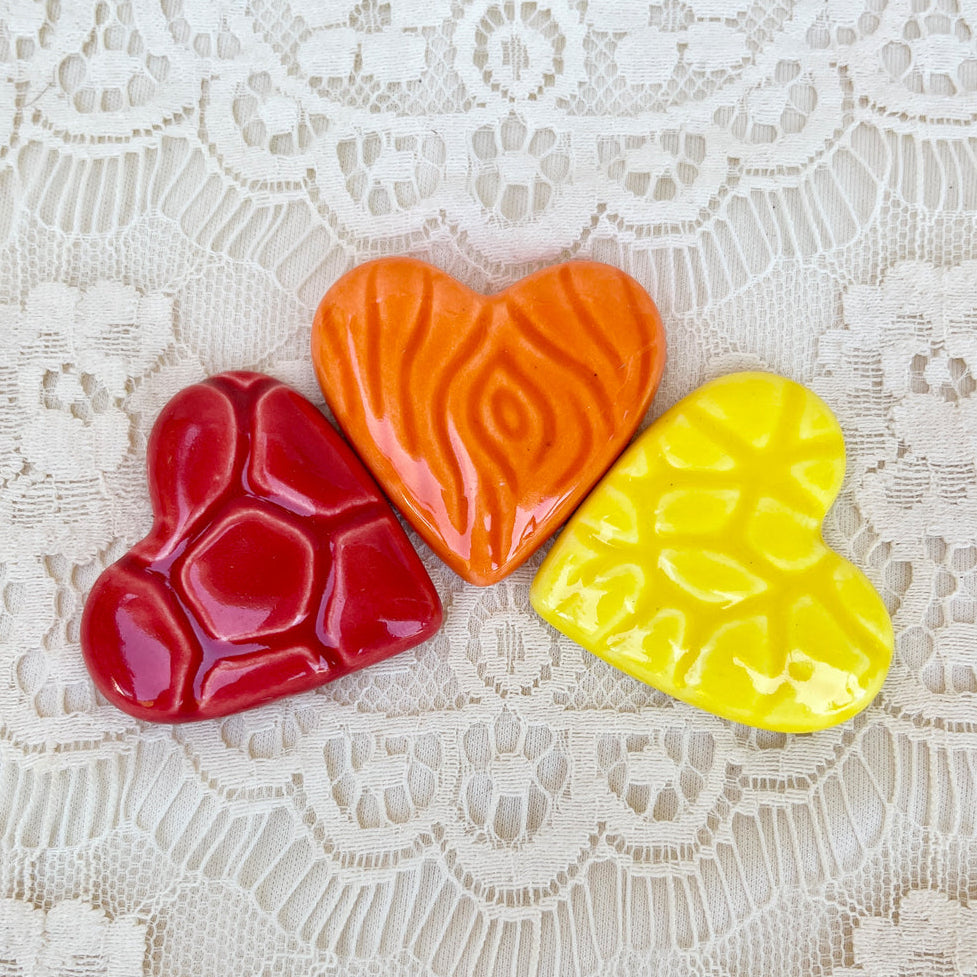 Three colored hearts (red, orange, yellow) on a lace background with text 'Colored Hearts Red Orange Yellow'.