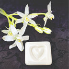 White ceramic with a heart design and white flowers on a dark background, labeled 'LOVE STONES'.