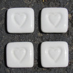 Four white stones with heart imprints on a dark surface, labeled 'Love Stones'.