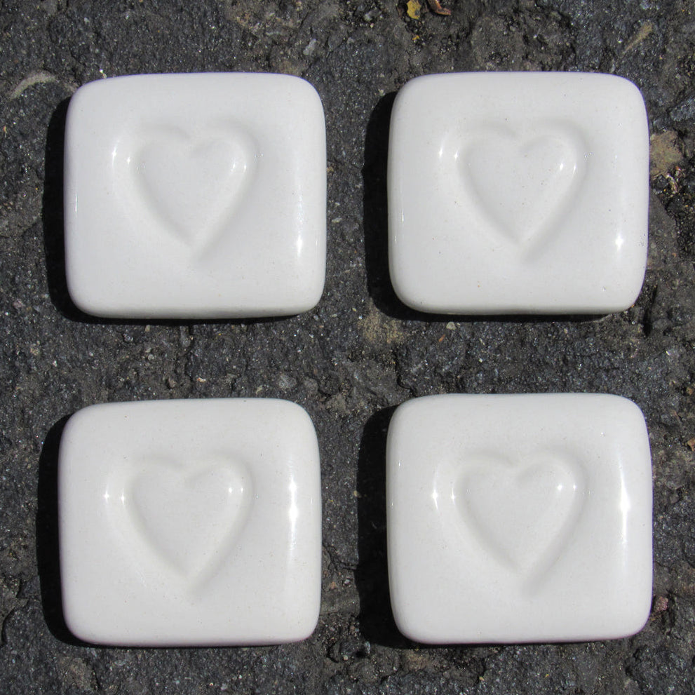 Four white stones with heart imprints on a dark surface, labeled 'Love Stones'.
